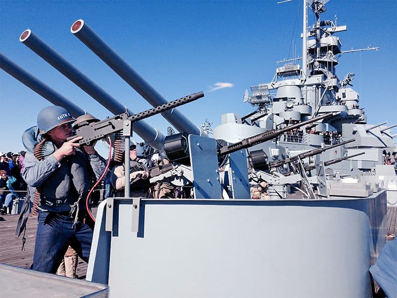 a man firing a machine gun on a museum ship