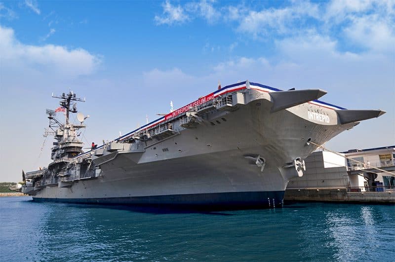 an aircraft carrier moored at a dock