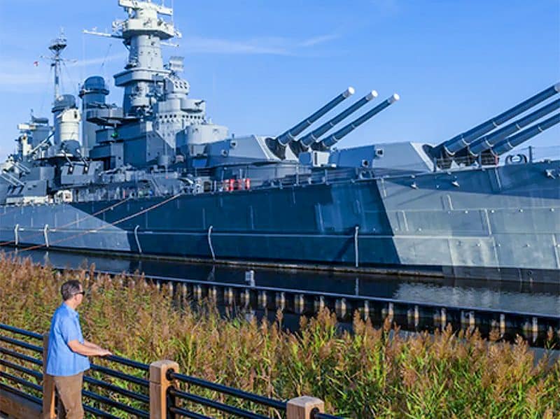 a man looking at a museum ship at anchor