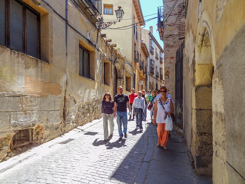 people walking down an ancient street in Segovia
