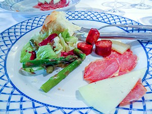 a dinner plate with cheese, meat and a salad