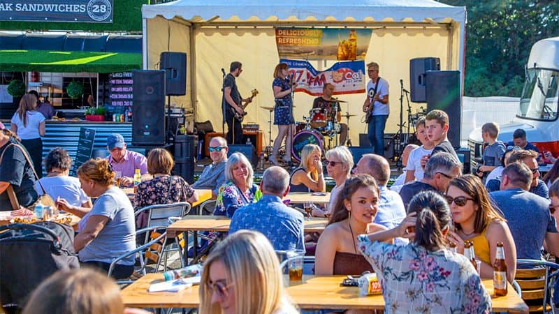 people sitting at outdoor tables in front of a band