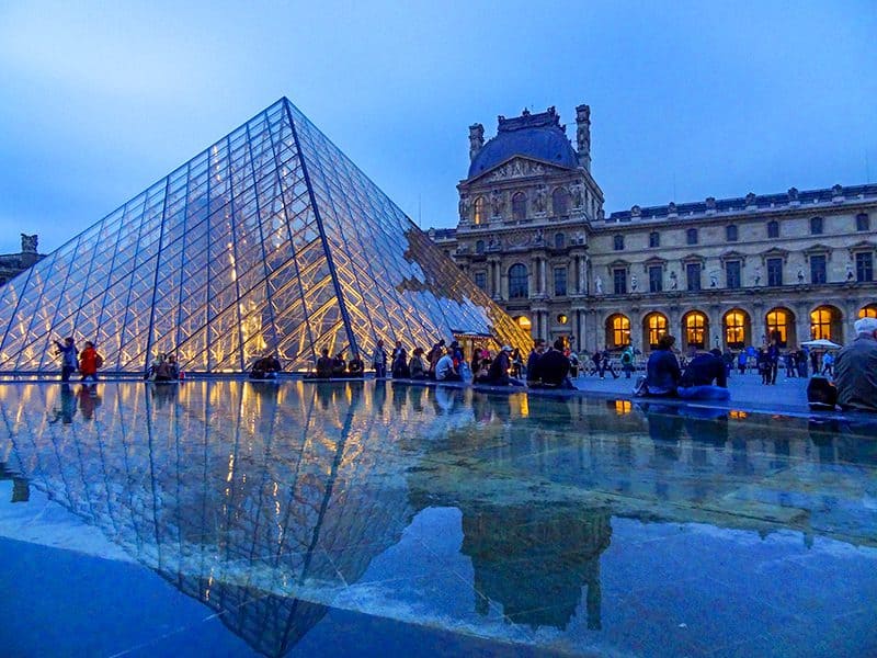 people sitting outside the Louvre Museum at dusk in the low season in Europe