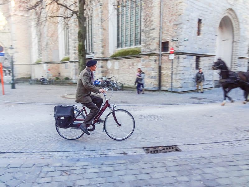 a man riding a bicycle on a cobblestone street  n the low season in Europe