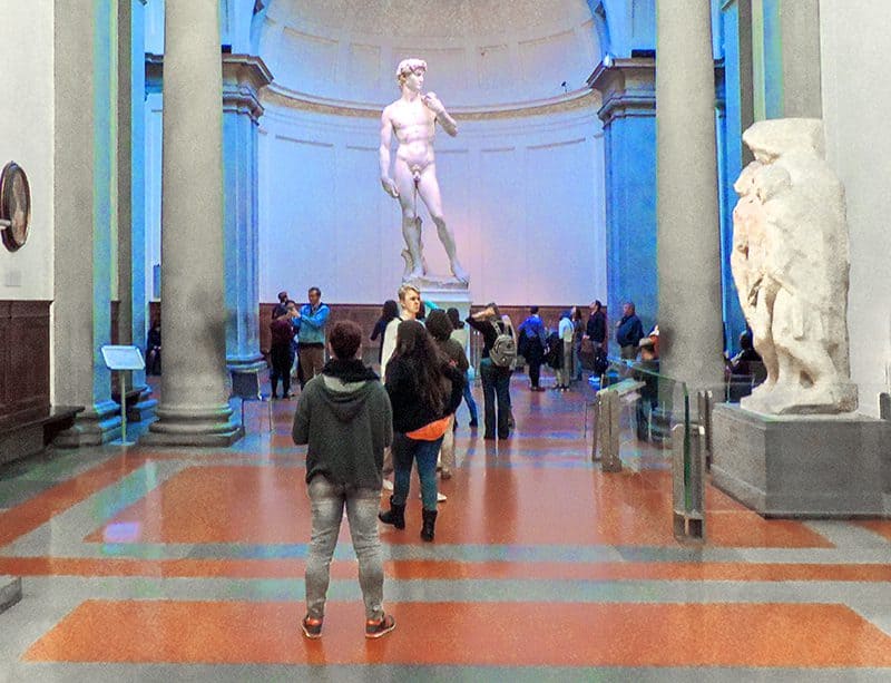 a small group of people looking at the statue of David in the low season in Europe