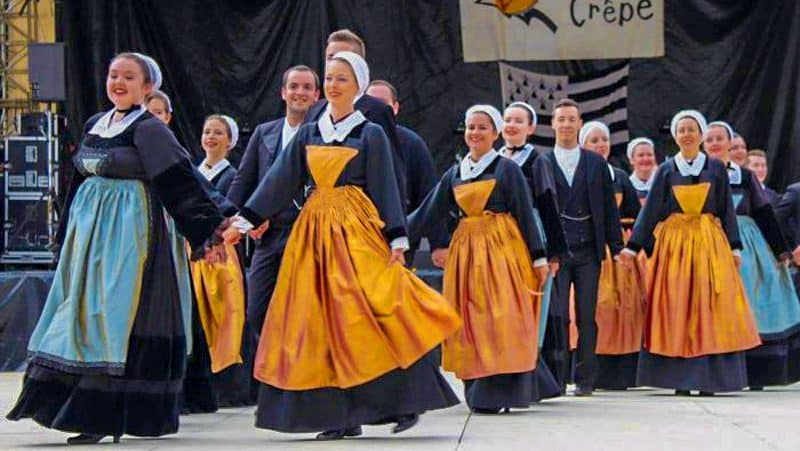 women and men in old costumes walking hand-n hand at one of the  food festivals in Europe in 2023