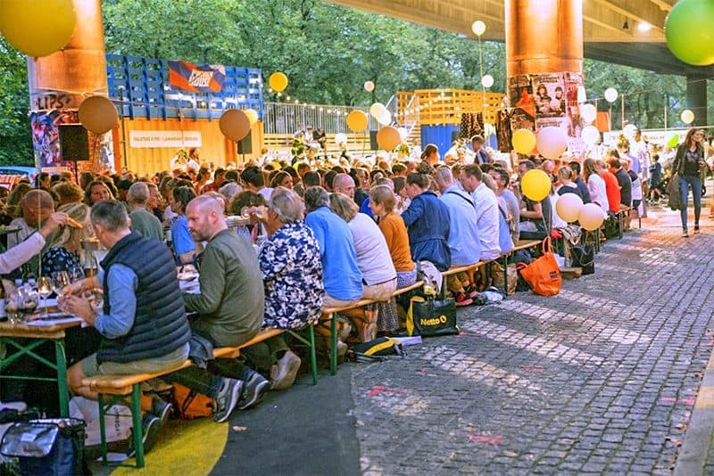 a large group of people sitting at a very long table - food festivals in Europe in 2023
