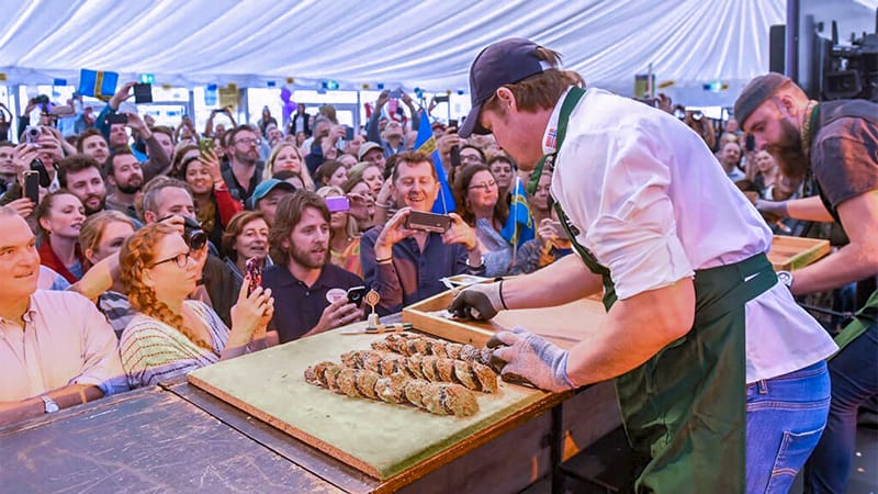 a man holding oysters in front of a large crowd