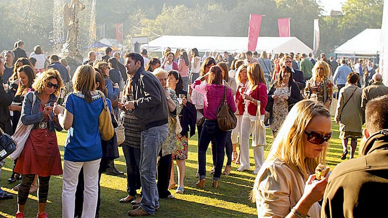 a large group of people having  drinks on a great lawn at sunset