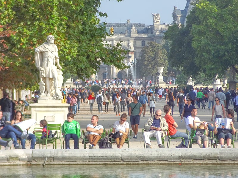 a crowd of people walking through a park near 18th-dentury buildings - seen while on walks in Paris 