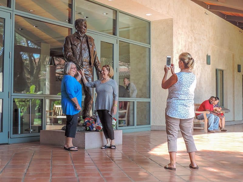 3 women taking a photo by a statue of Ronald Reagan in the presidential museum of Reagan