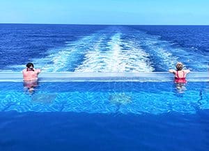 two people in an infinity pool on the stern of a ship at sea