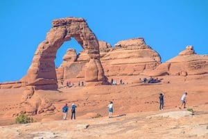 people looking at a huge natural rock arch in one of the Utah National Parks