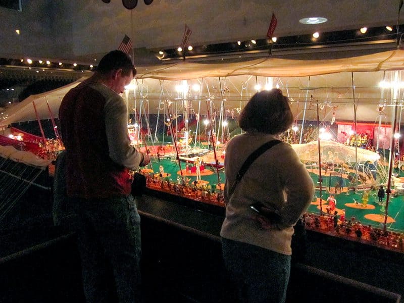 people looking at an exhibit of a miniature circus in a small museum