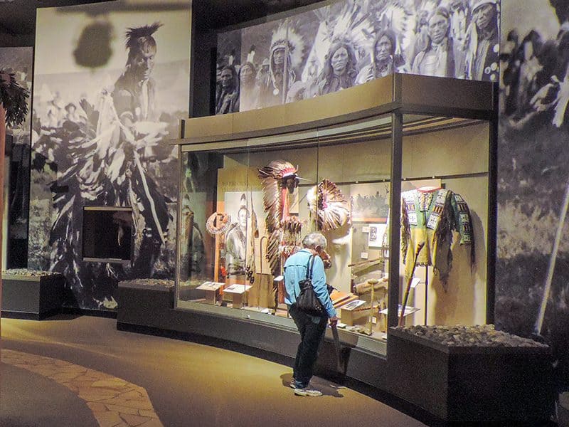 a woman looking at memorabilia of native Americans in a museum