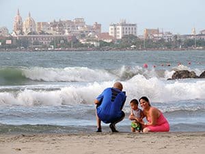 a couple on a beach taking a photo of a young child in Cartagena Colombia