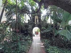 a couple walking towards an archway leading to a shaded garden