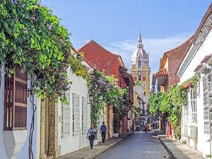 a colorful small street with a church tower at its end in Cartagena Colombia