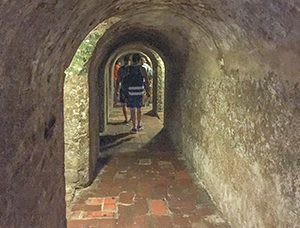 people walking through a tunnel in an ancient fort