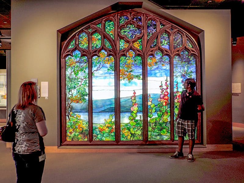 2 women admiring a large Tiffany stained glass window