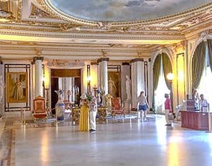 people in an ornate ballroom in a small museum