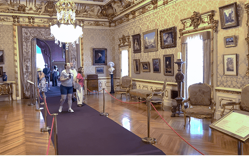 people walking through an ornate room  in a small museum