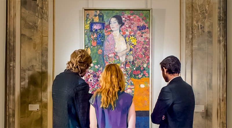 3 people admiring a large paiting in a museum