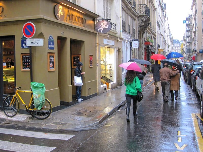 people with umbellas on a narrow street in PAris