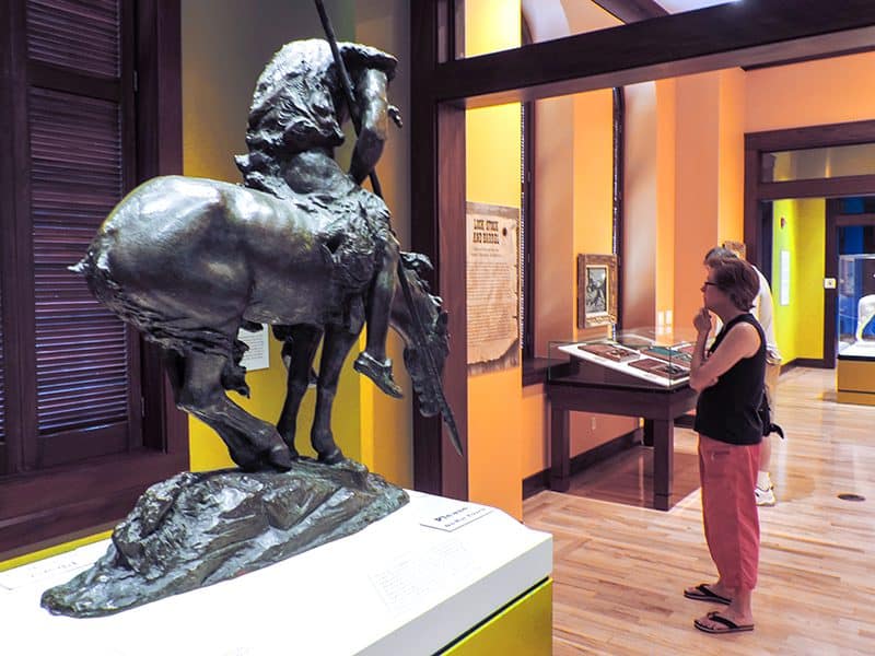 a woman looking at a piece of western art in a museum