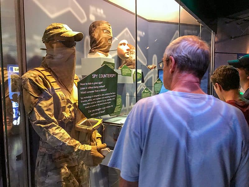 a man looking at an exhibit of a masked man