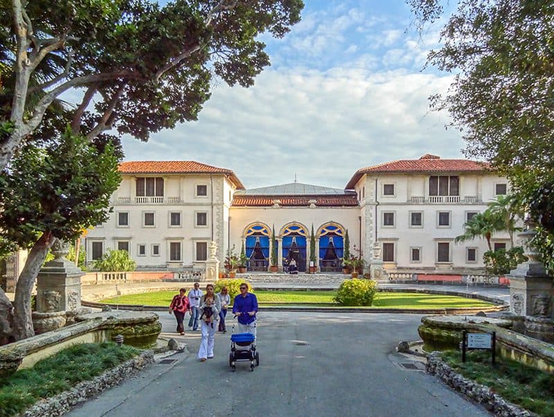 people walking outside a large old mansion