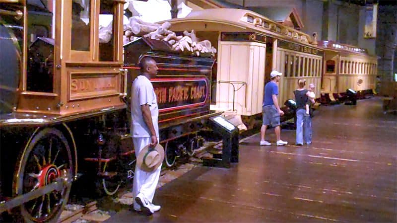 people standing by an old train  in a small museum