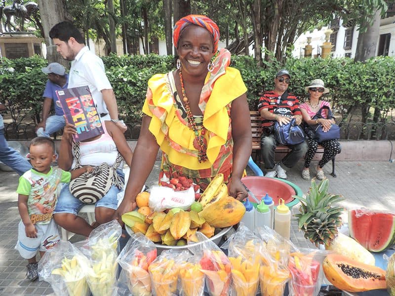 a woman in a colorful peasant dress selling fruit in Cartagena Colombia