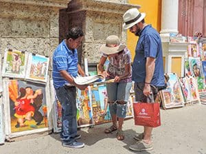 people looking at paintings displayed along the sidewalk