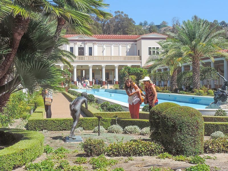 two woman looking at a statue by a pool  in a small museum