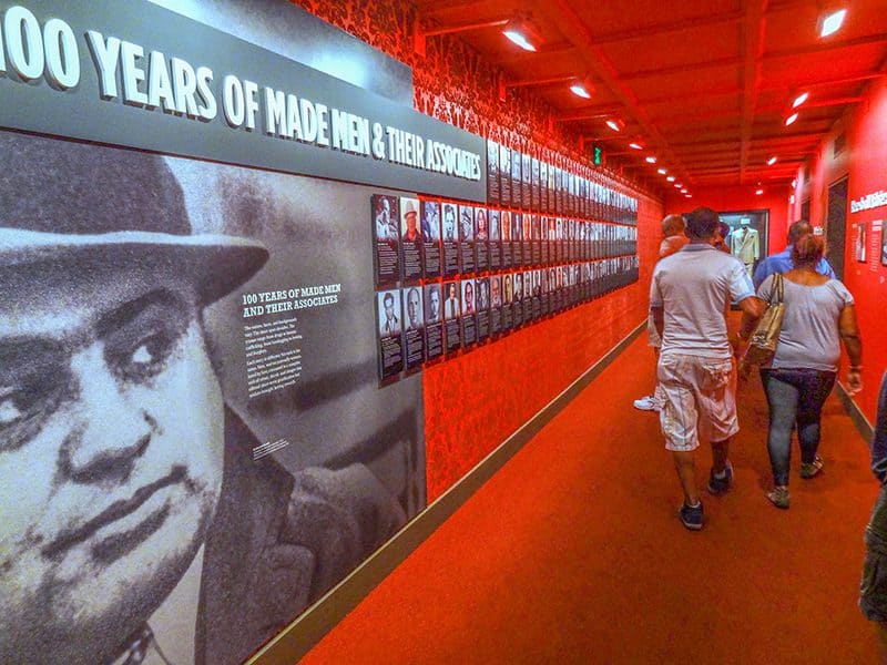 people walking past a large photo of a criminal