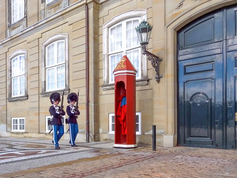 two guards marching past a bright red guard stand