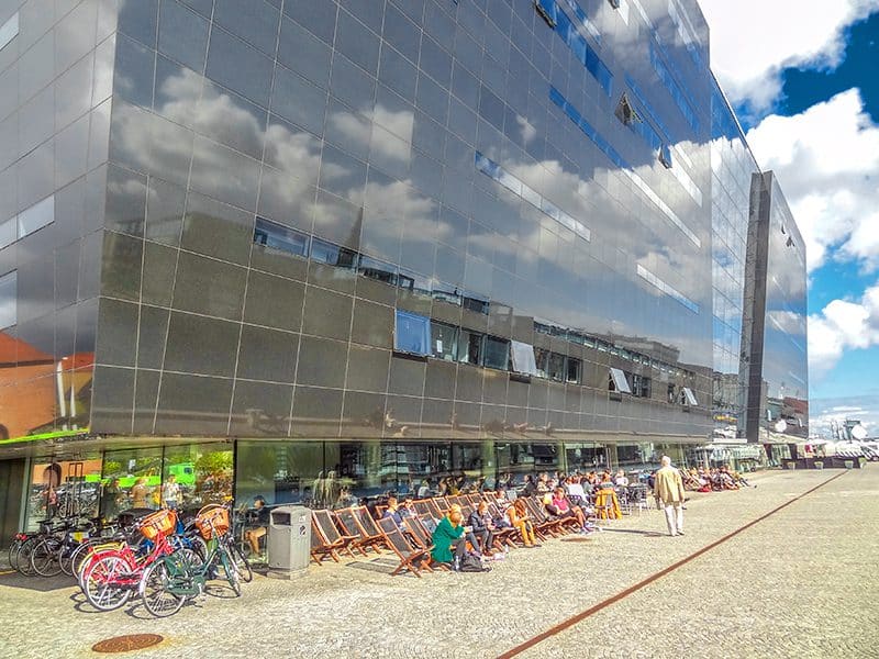 people sunning themselves outside a modern black building