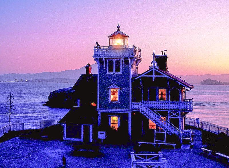 a man atop one of the Victorian U.S. lighthouses at sunset
