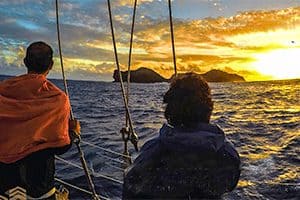 people on a boat looking at the sun set