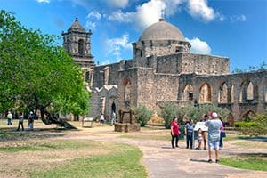 people walking towards a large stone church in the San Antonio Missions, one of the World Heritage sites in the USA