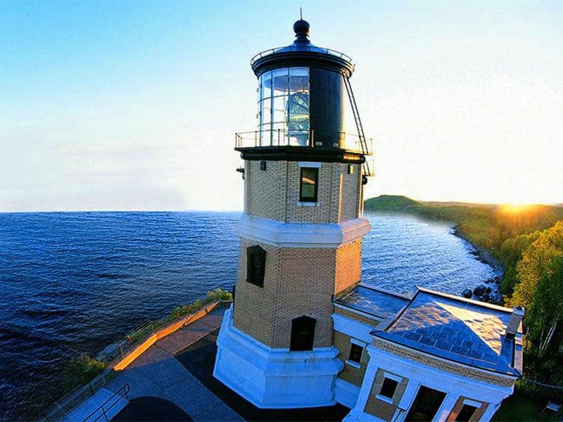 an ornate yellow-brick lighthouse at sunset