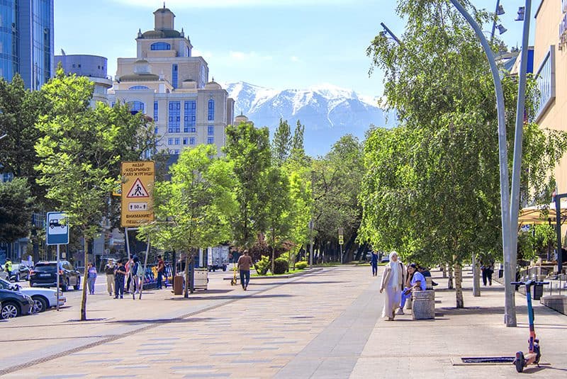 people walking along a broad street with mountains in the background, seen on a visit to almaty kazakhstan