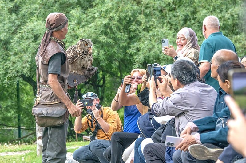 people taking photos of a many holding an owl, seen on a visit to almaty kazakhstan