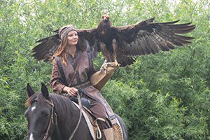 a woman on a horse hold a large eagle