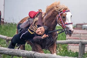 an acrobat riding on the side of a horse