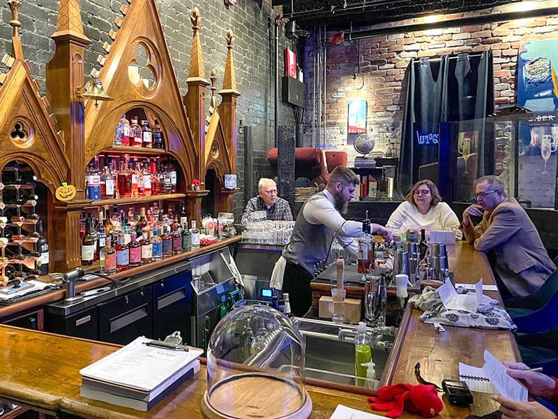 people seated at a bar with furniture from an old church