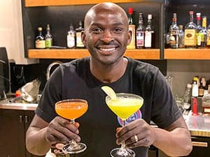a mixologist holding two drinks