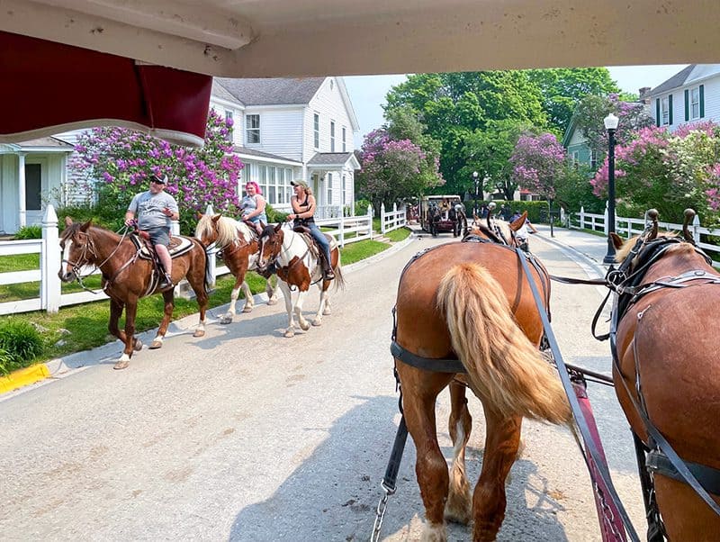 people on horses riding along a street