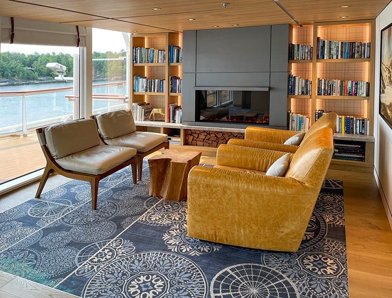 a lounge with a fireplace, bookcase and comfortable seats aboard the Viking Octantis